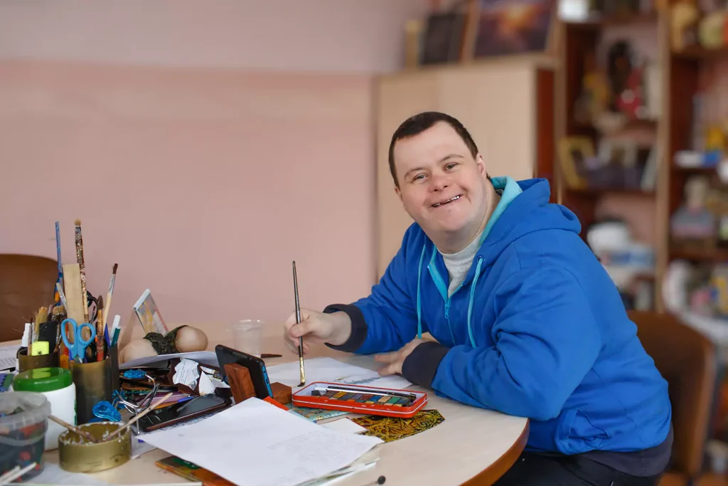Disabled man in art class smiling at camera