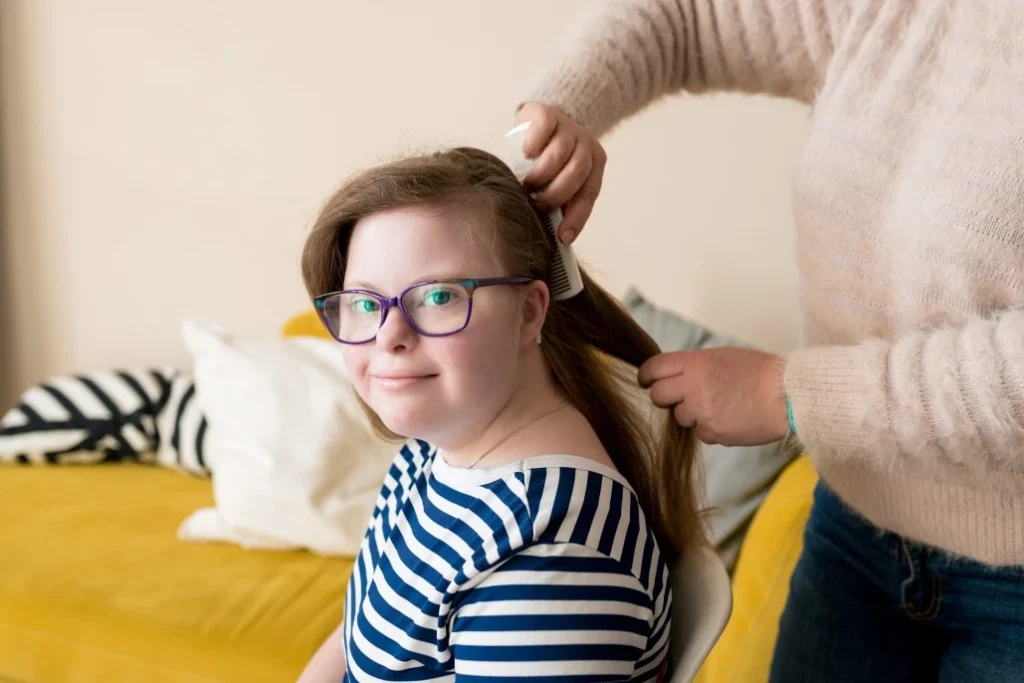Disabled woman with down syndrome having hair brushed