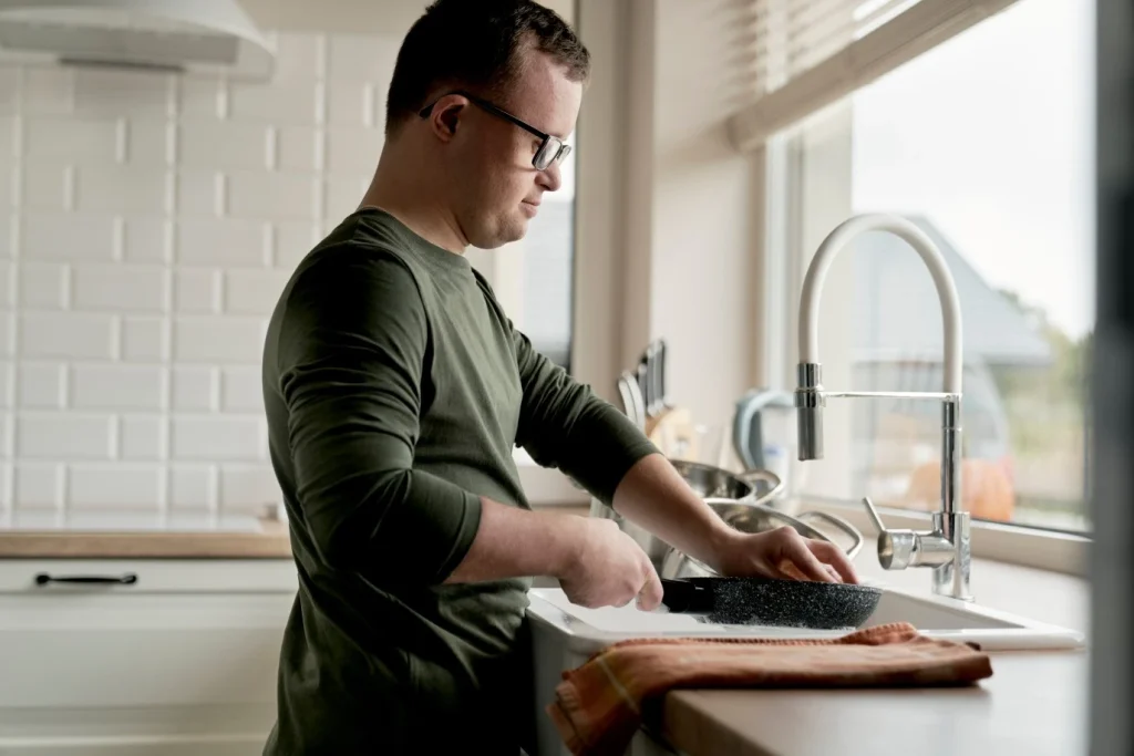 Disabled man with down syndrome doing the dishes at home