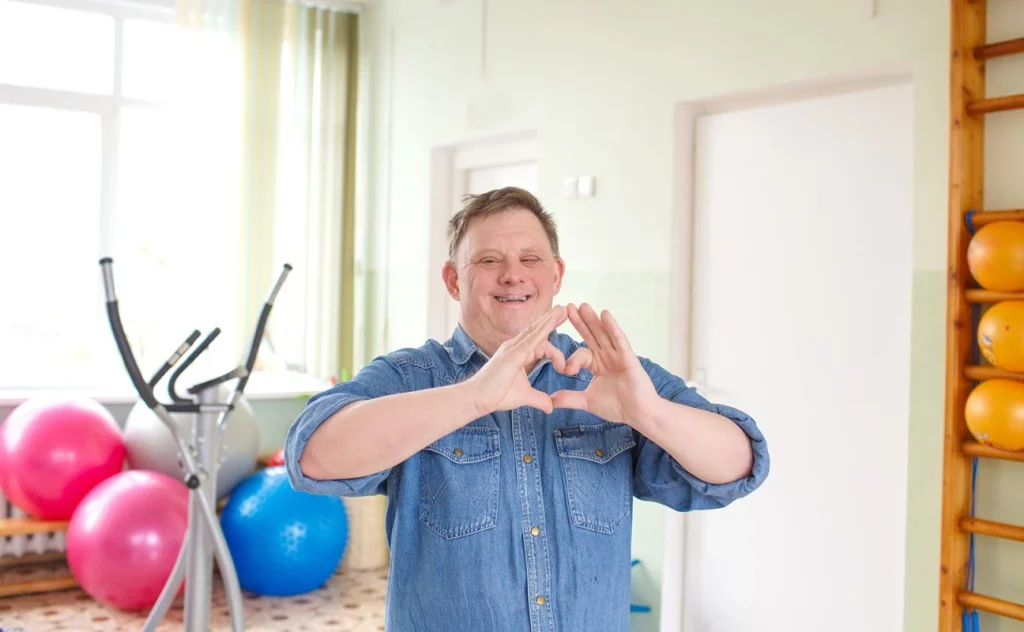 Disabled man making love heart shape with hands and smiling at camera